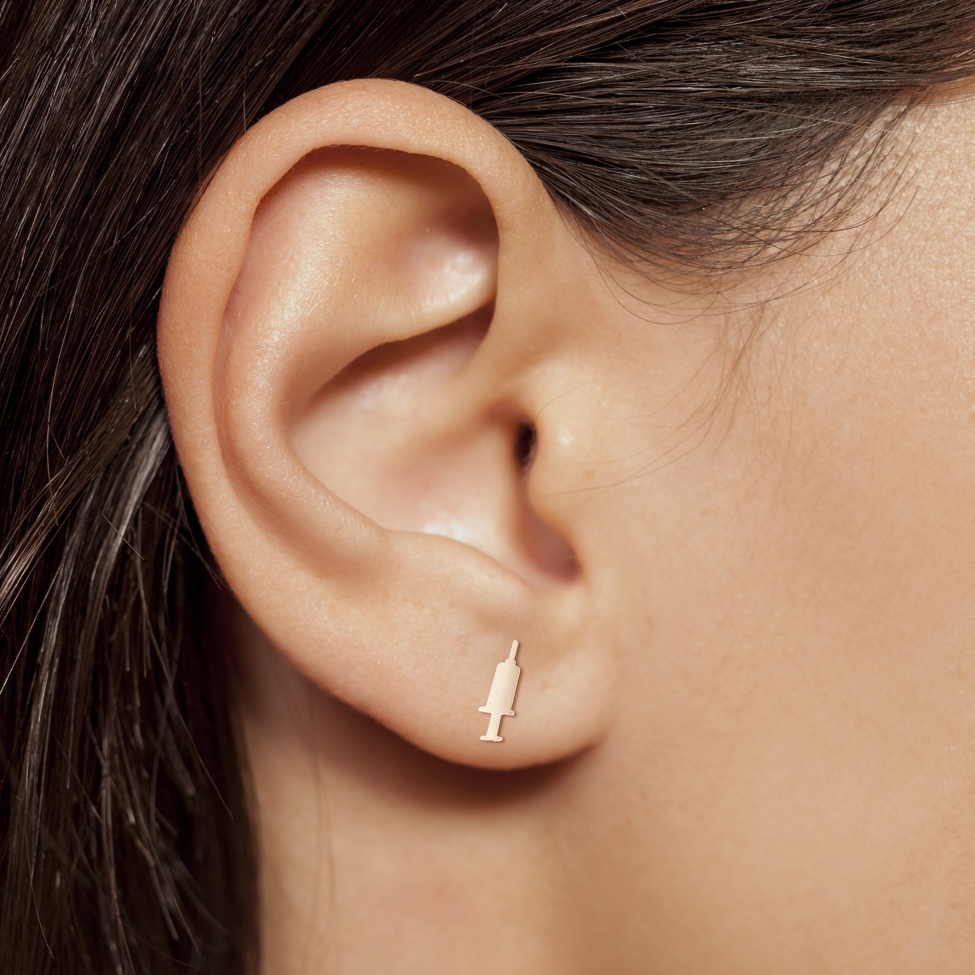 Syringe earring in rose gold on nurse model ear